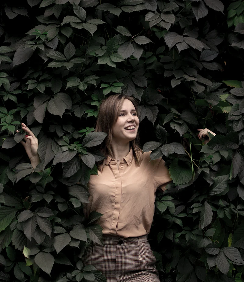 Woman surrounded by green leaves, representing personalised strategy, emotional growth, and inner transformation.
