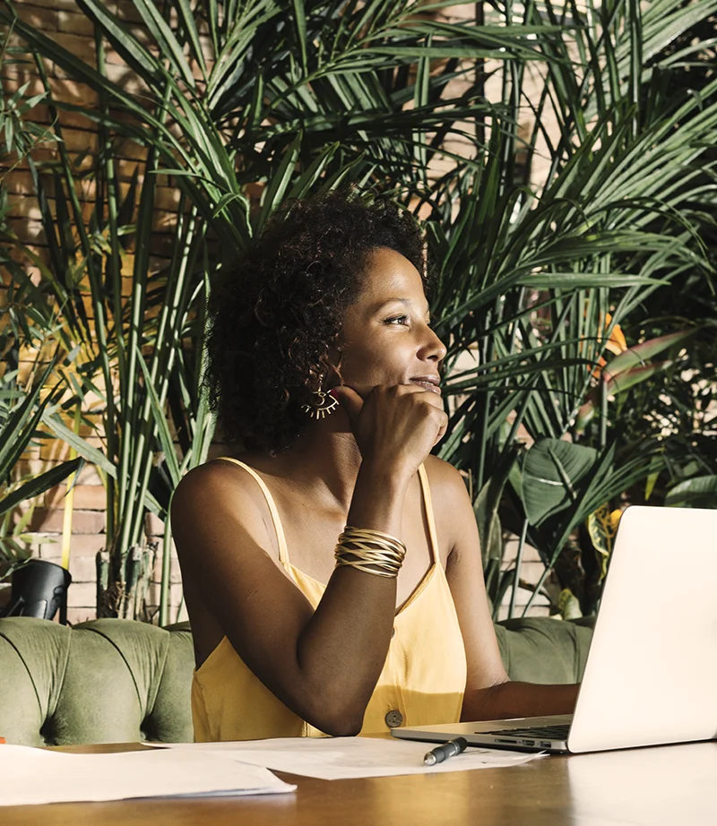 Woman in a calm indoor setting with a laptop, representing a safe and secure online hypnotherapy environment.