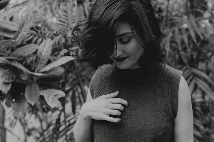 Black and white portrait of Esné with her hand near her heart, representing circles, workshops, intuition, and embodied presence.