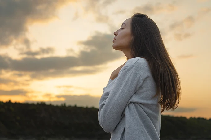 Woman standing outdoors at sunset, representing embodied transformation, somatic integration, and inner emotional change.