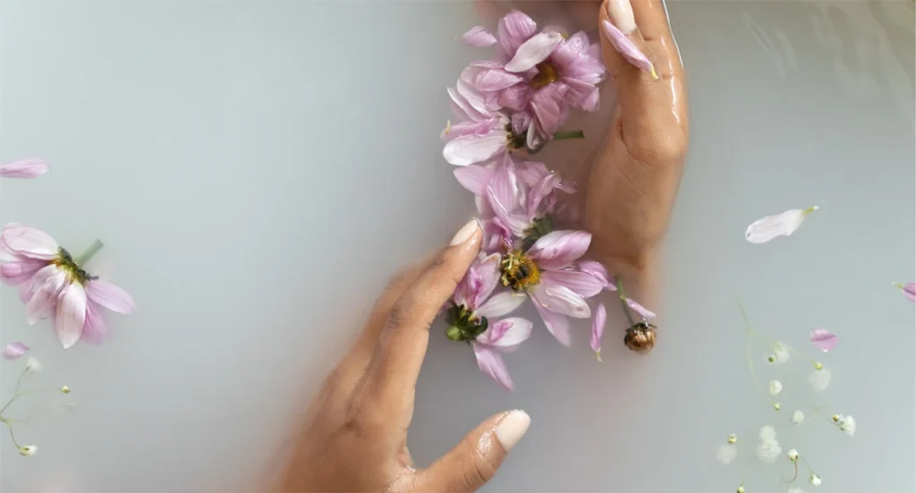 Hands moving gently through water and flowers, representing inner child work, parts work, and healing beneath the surface.