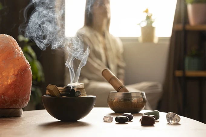 Encens, objets de bien-être et silhouette floutée en arrière-plan représentant une séance de régression dans les vies antérieures en ligne dans un cadre apaisant.