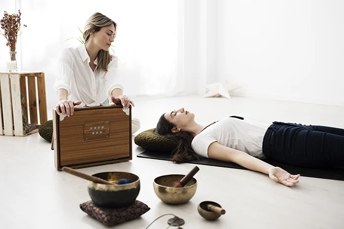 Femme allongée lors d’une séance de régression dans les vies antérieures en présentiel, accompagnée par une praticienne dans un cadre apaisant.