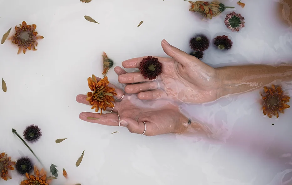 Hands resting in water with flowers, symbolizing different coping patterns shaped by childhood experience.