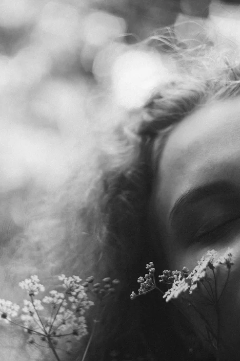 Femme parmi des fleurs représentant les émotions difficiles et la conscience de soi