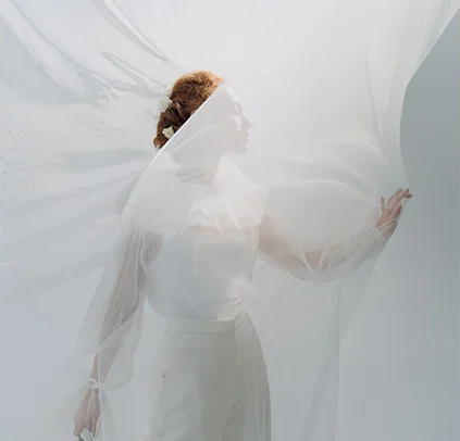 Woman surrounded by flowing fabric representing trauma recovery and somatic healing